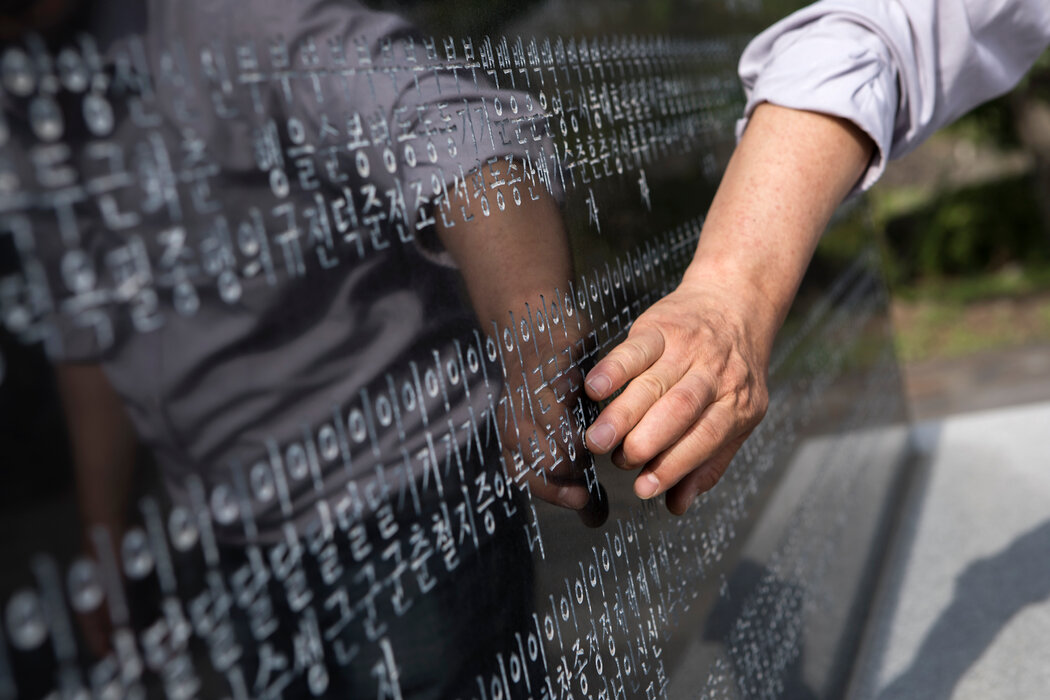 一名男子指着纪念碑上祖父的名字。“实际上,每个济州人都是幸存者、目击者、失去家人的悲痛者,”韩江说。